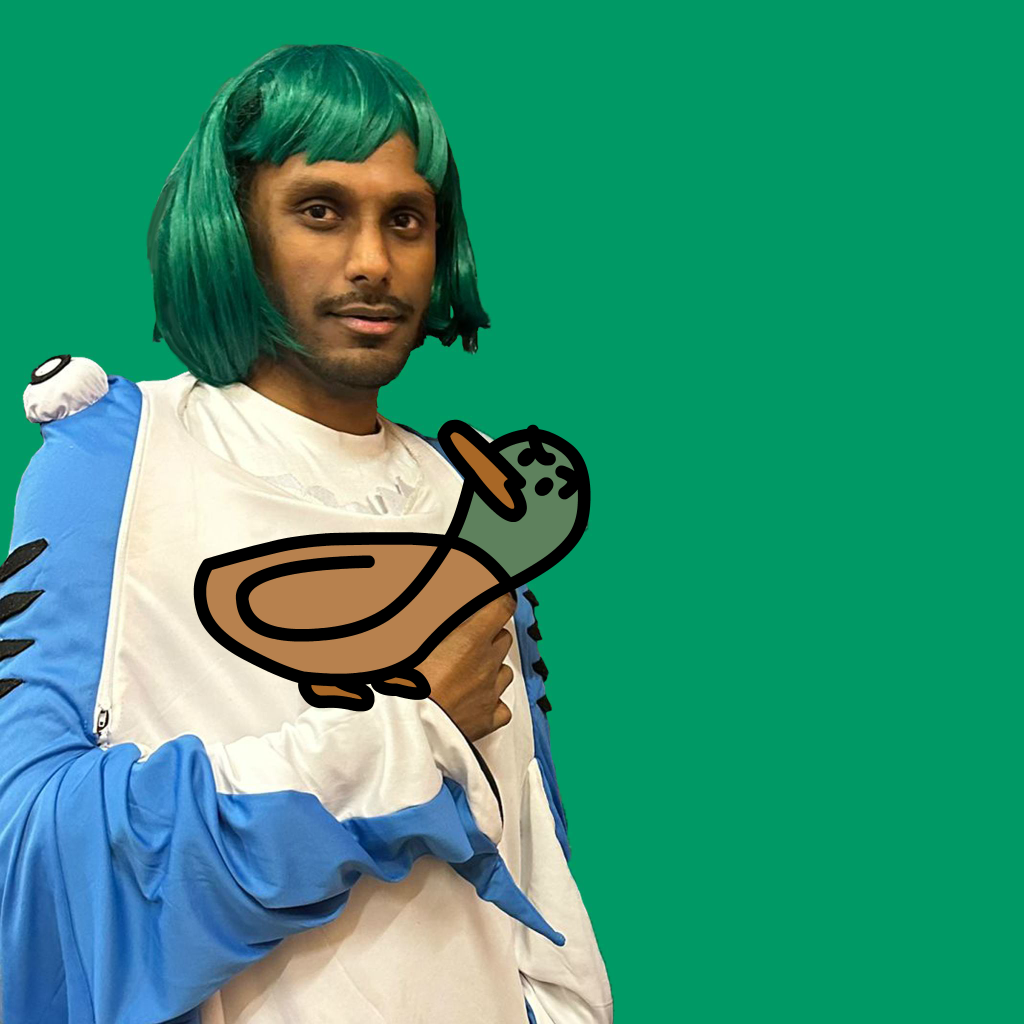 Ritish in a shark costume and a green wig with a duck on his arm that looks at him judgingly.